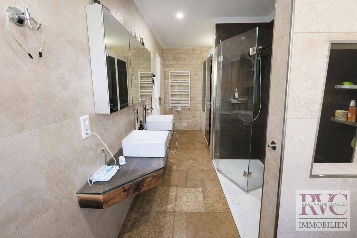 Modernes Badezimmer mit Doppelwaschbecken, großer begehbarer Dusche und beheiztem Handtuchhalter.