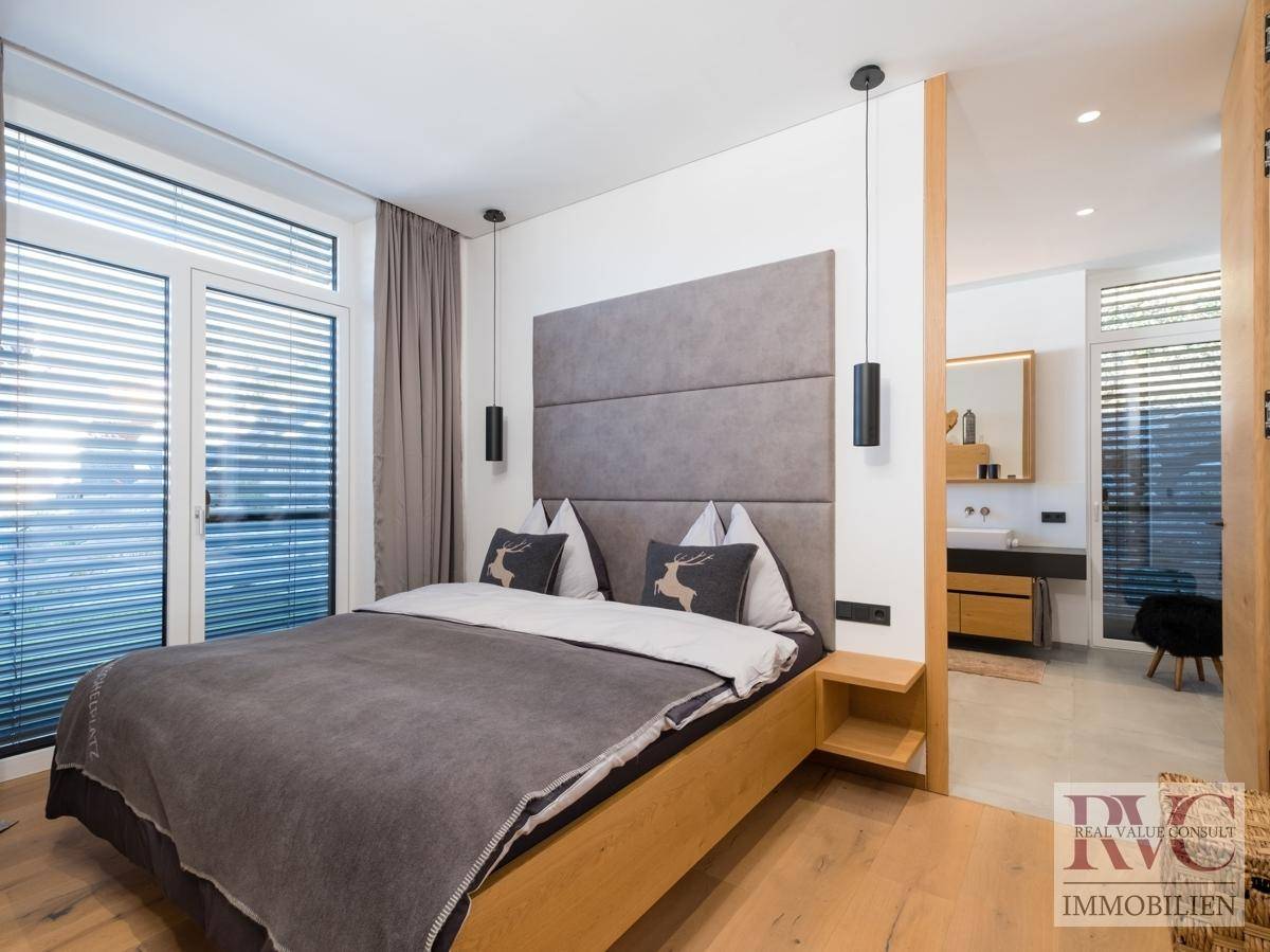 Gemütliches Schlafzimmer mit Holzboden, Zugang zum Balkon und angrenzendem Badezimmer.