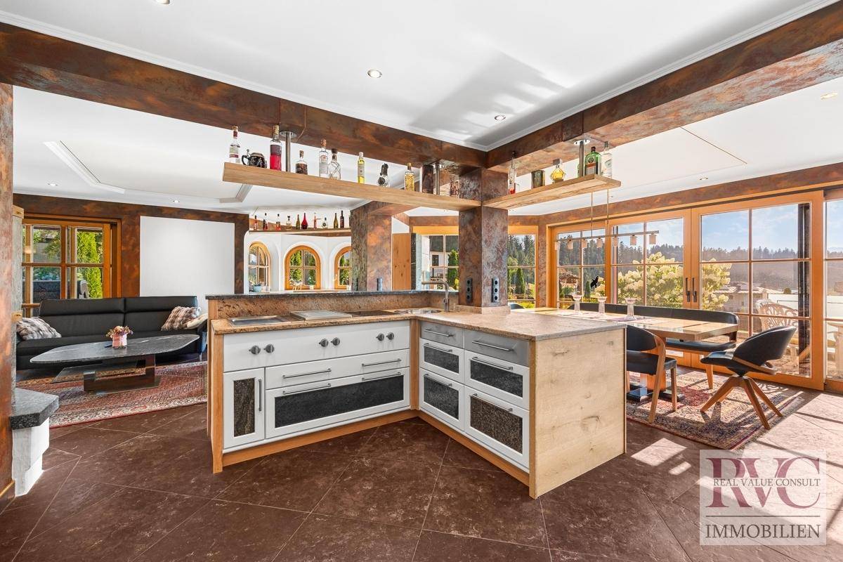 Offene Küche mit Kochinsel und Essbereich, verbunden mit dem Wohnzimmer und Zugang zur Terrasse.