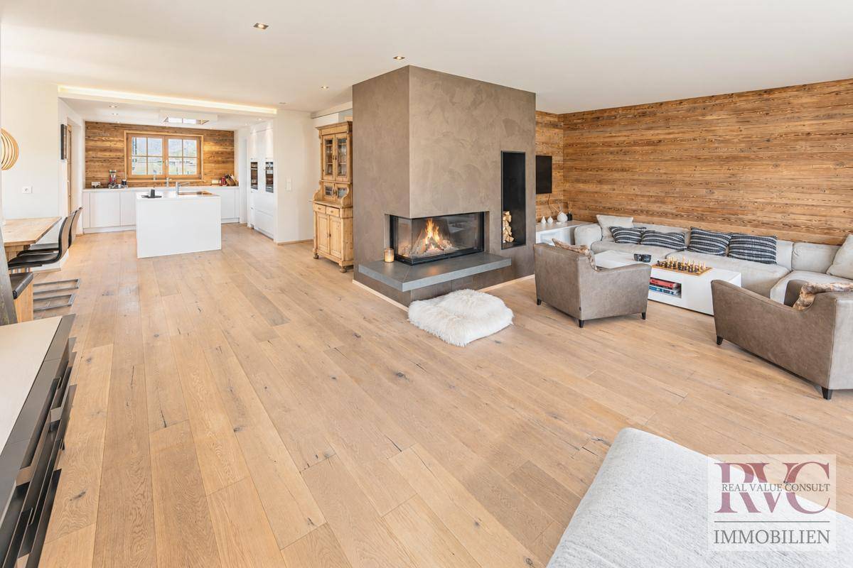 Offener Wohn- und Essbereich mit Holzboden, Kamin und integrierter Küche.