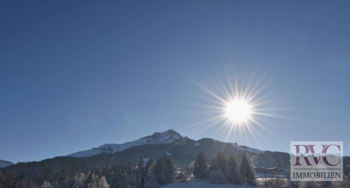 Sonniger Wintertag mit strahlendem Himmel und schneebedeckten Bergen im Hintergrund.