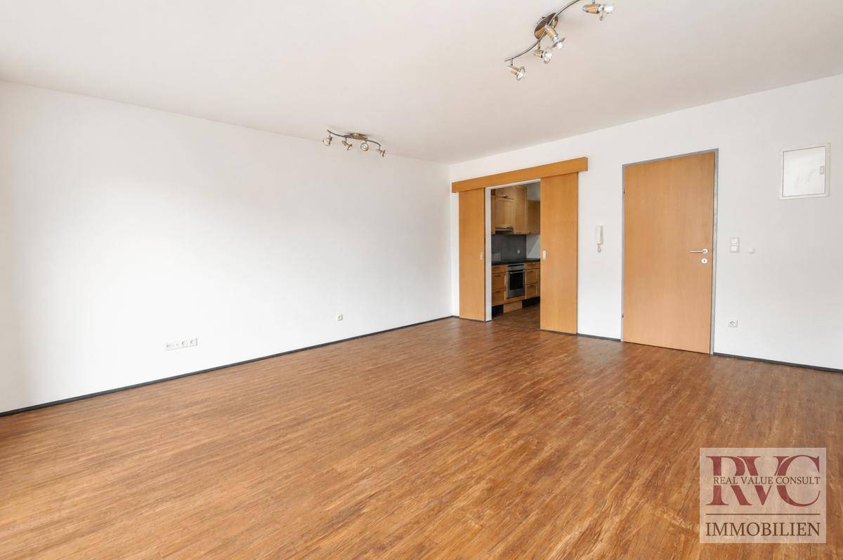 Geräumiger Raum mit Holzboden und Schiebetür zur Küche.