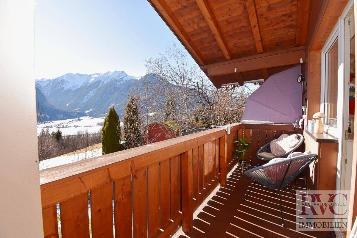 Gemütlicher Holzbalkon mit Sitzgelegenheiten und weitem Blick auf die umliegende Berglandschaft.