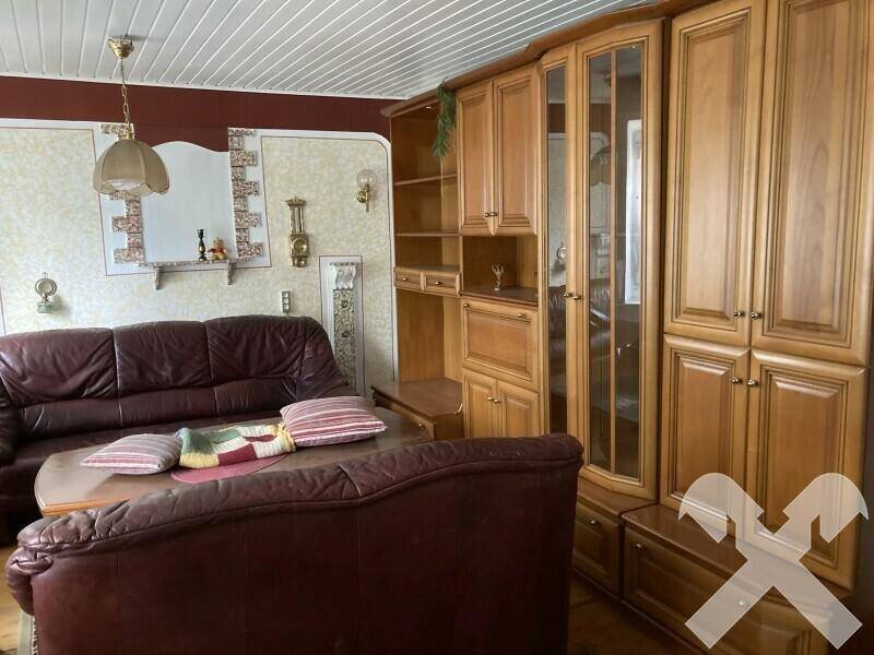 Gemütliches Wohnzimmer mit Ledersofa, Holzschrankwand und traditioneller Beleuchtung.