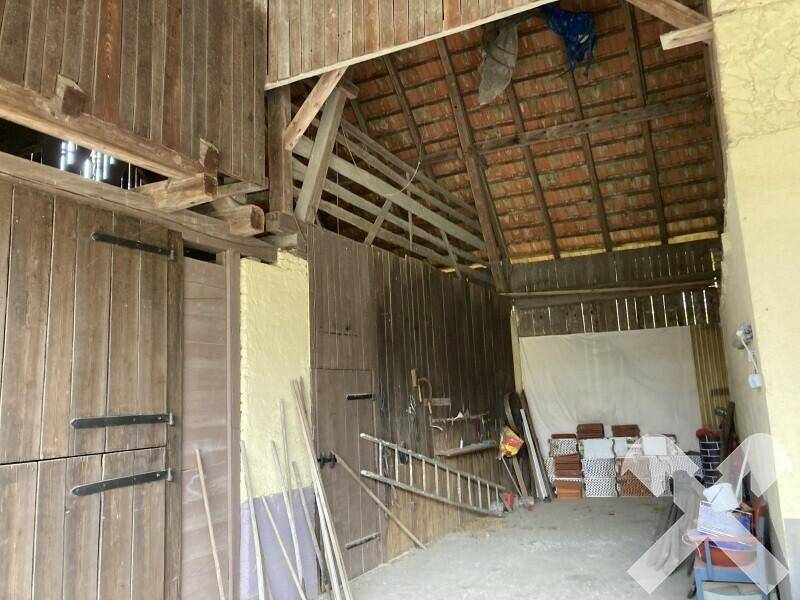 Innenansicht einer Scheune mit Holzbalken, offenem Dachstuhl und Lagerflächen.