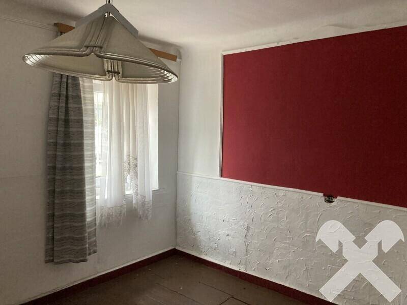Kleiner Raum mit roter Akzentwand, weiß gestrichenen Wänden und einem Fenster mit Vorhängen.