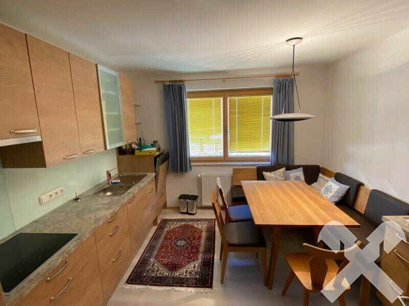 Funktionale Küche mit Holzelementen, Essbereich und Fenster mit Jalousien.