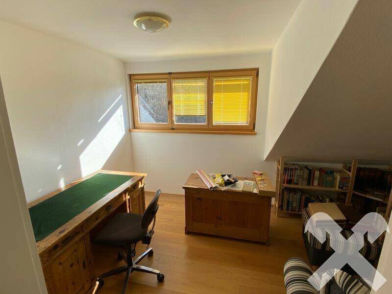 Helles Arbeitszimmer mit Holzschreibtisch, Bücherregal und Dachschräge.