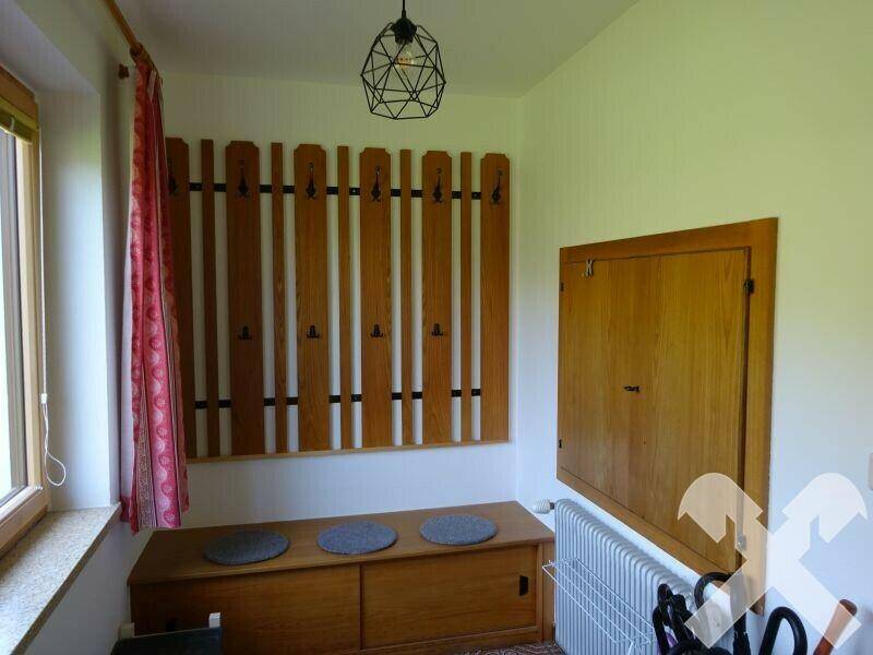 Gemütlicher Eingangsbereich mit Holzgarderobe, Sitzbank und Heizkörper.