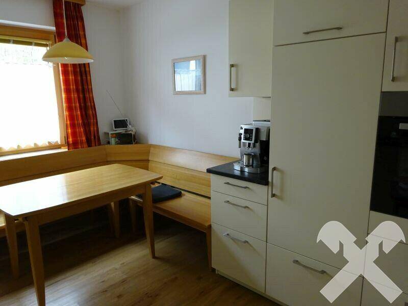 Helle Küche mit Essecke, Holzbänken und modernen Einbauschränken.