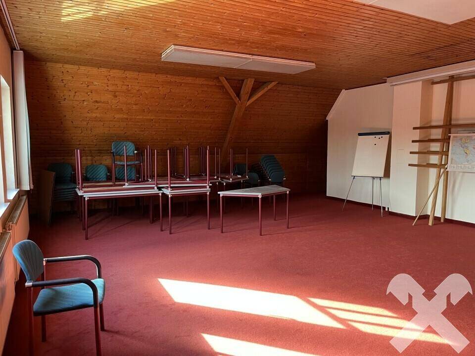 Geräumiger Konferenzraum mit rotem Teppichboden, Holzverkleidung und natürlichem Lichteinfall durch die Fenster.