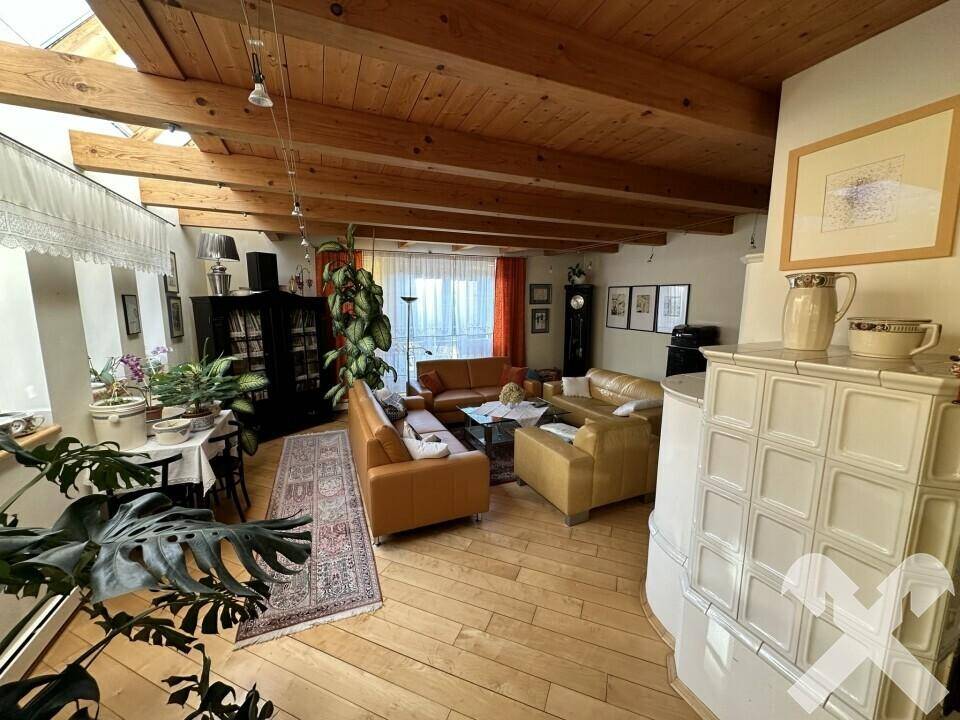 Helles Wohnzimmer mit Holzbalkendecke, Parkettboden und bequemen Ledersofas.