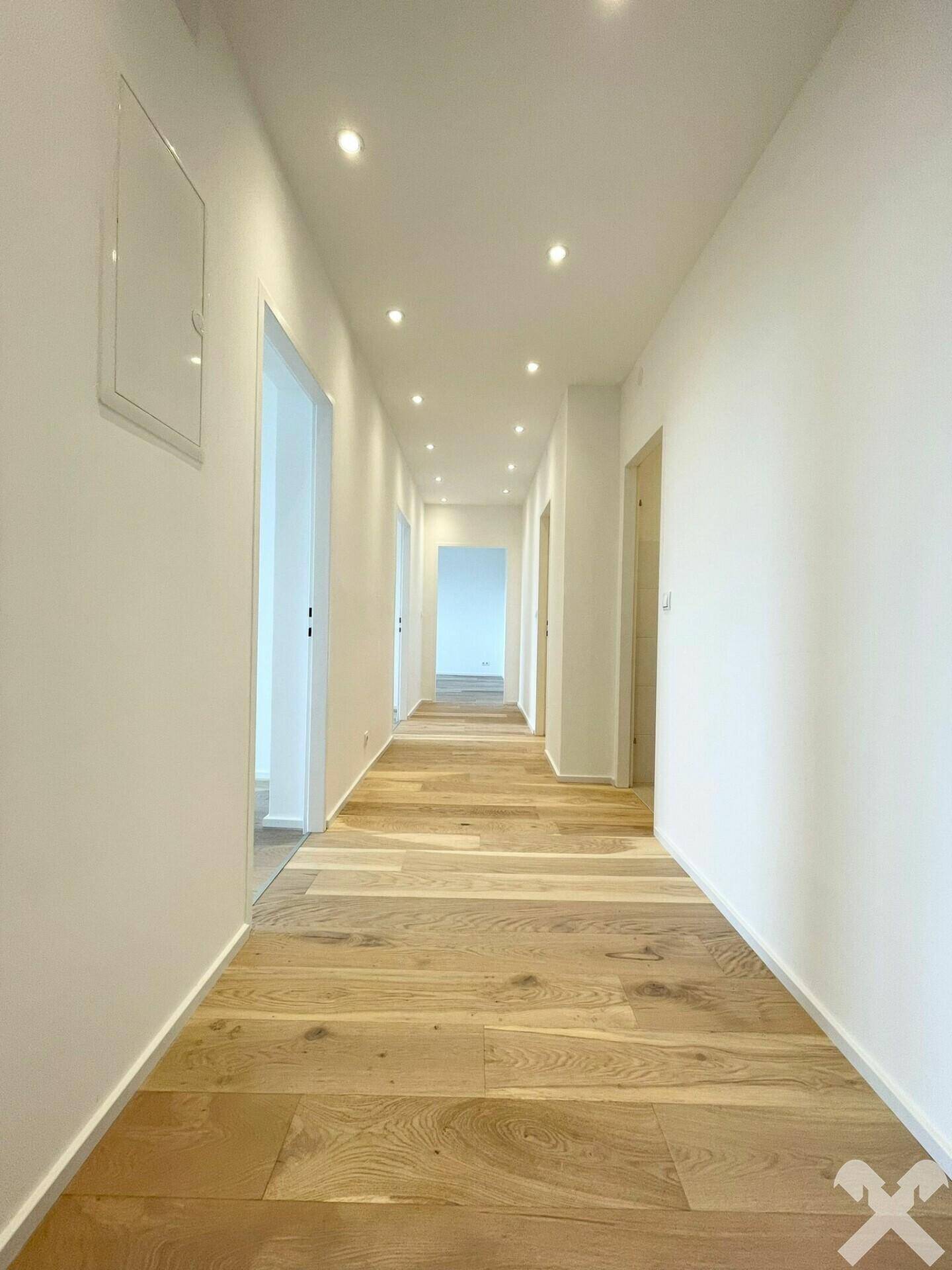 Heller Flur mit modernem Holzplankenboden und integrierten Deckenstrahlern.