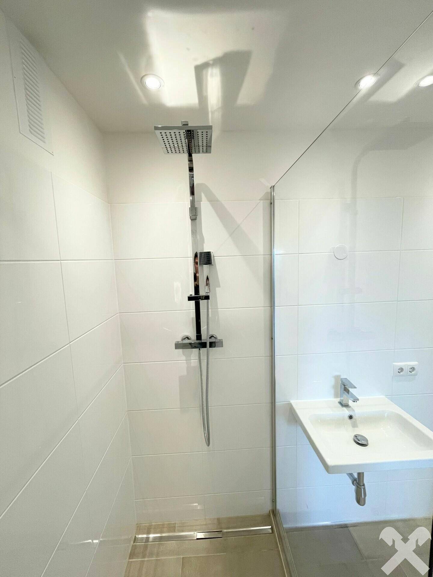 Detaillierte Ansicht der modernen Dusche mit Regenduschkopf und Glasabtrennung im Badezimmer.