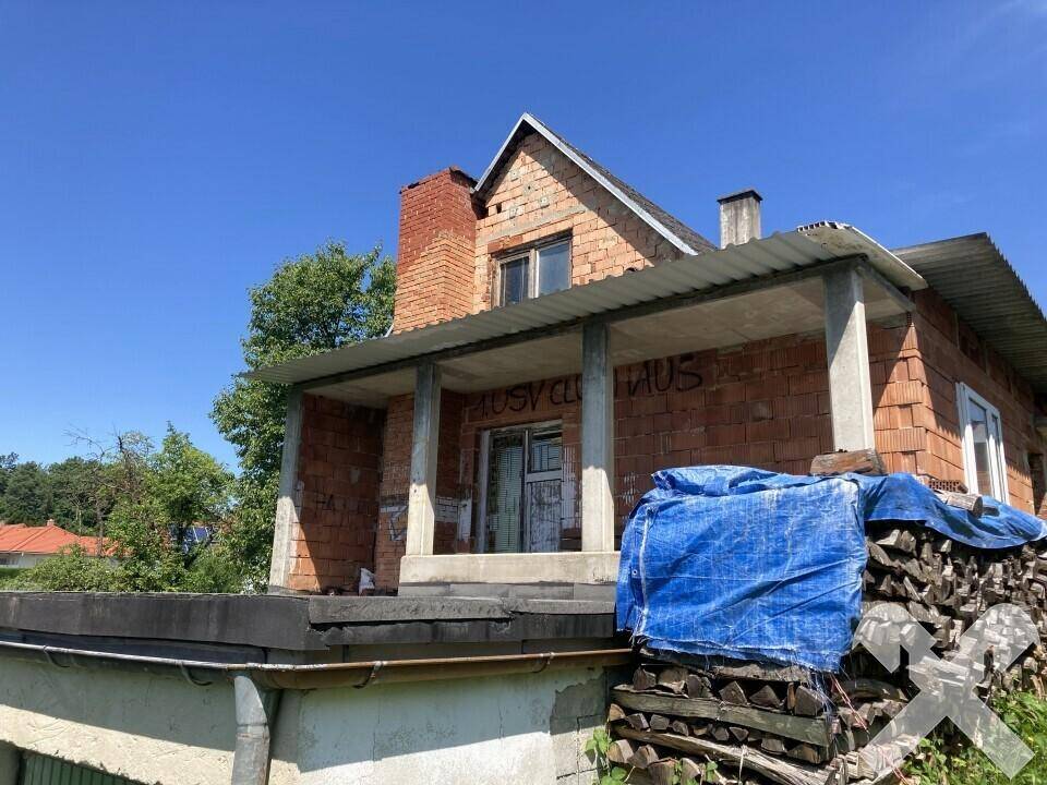 Detailansicht des überdachten Eingangsbereichs des Backsteingebäudes mit Säulen und Graffiti.