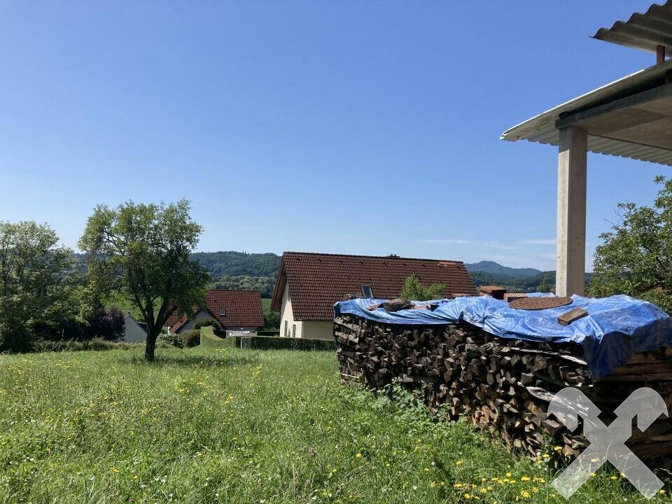 Weitläufige Aussicht über grüne Wiesen auf andere Häuser und bewaldete Hügel in der Ferne.