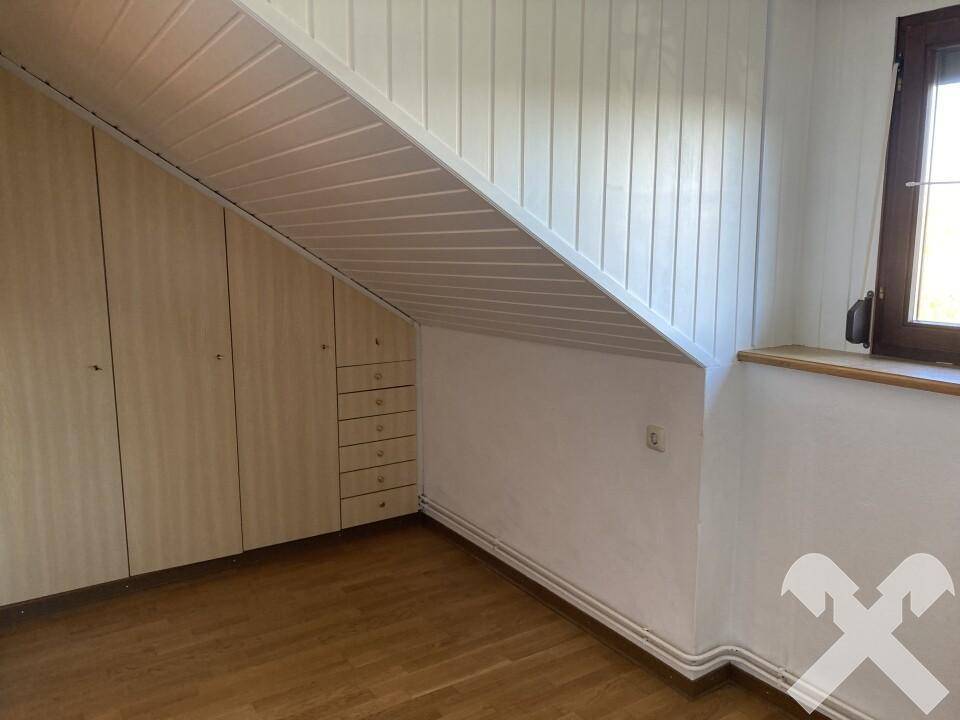 Dachzimmer mit maßgefertigten Einbauschränken unter der Dachschräge und Parkettboden.