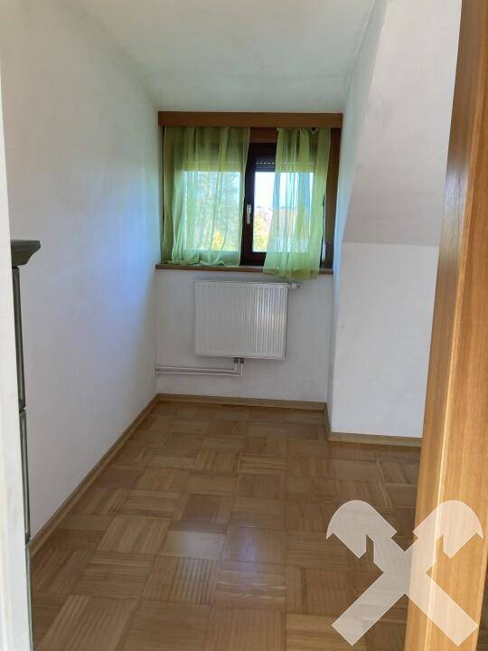 Kleiner, heller Raum mit Fenster, grünen Vorhängen und Parkettboden, ideal als Kinderzimmer oder Büro.