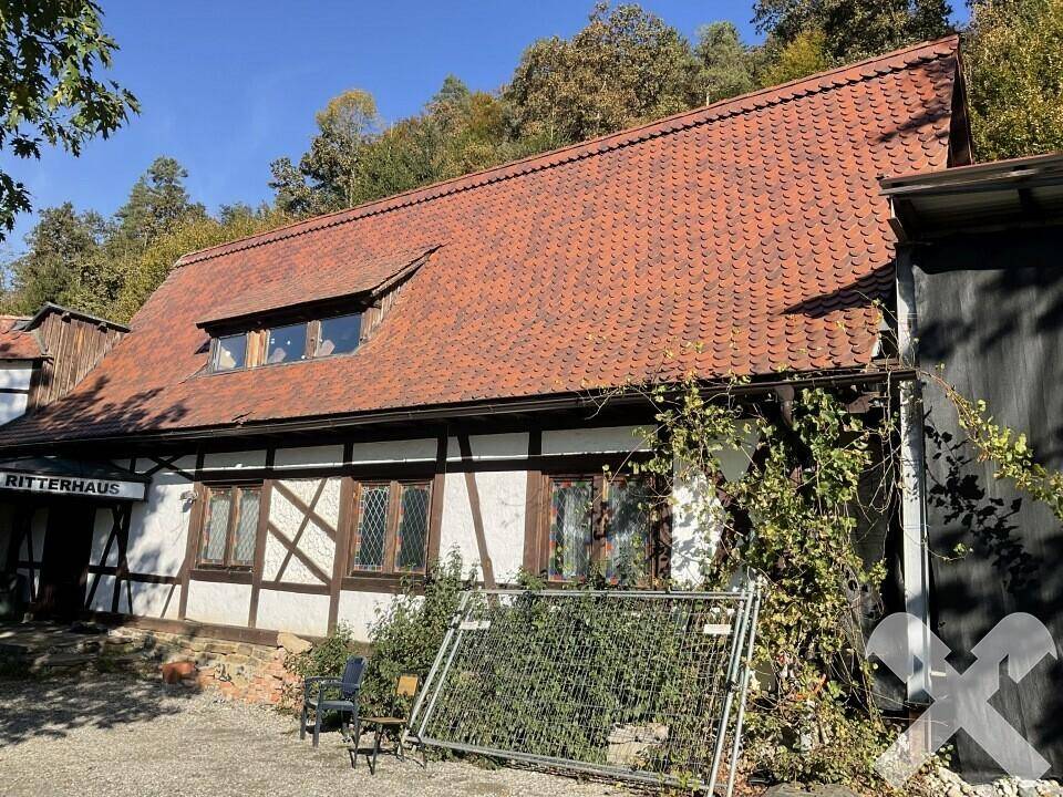 Nahaufnahme eines traditionellen Gebäudes mit Fachwerk, Ziegeldach und bewachsenen Wänden.