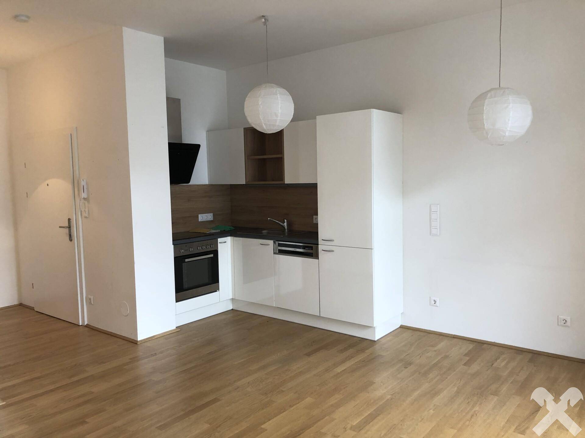 Moderner offener Küchenbereich mit weißen Hochglanzschränken und integrierten Geräten, kombiniert mit Holzboden.