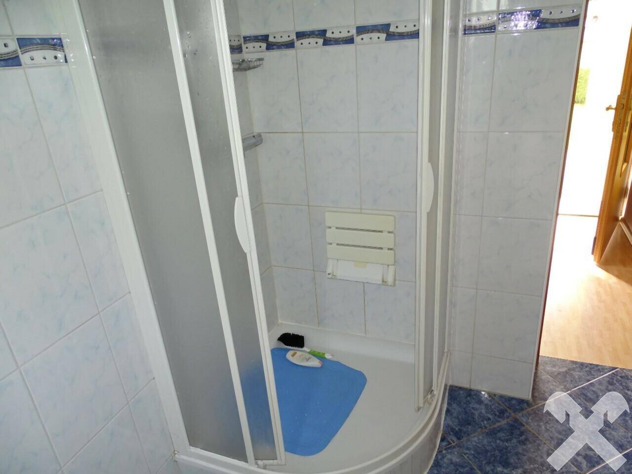 Duschkabine in einem Badezimmer mit weißen und blauen Wandfliesen.