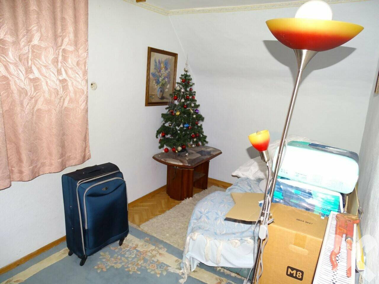 Kleiner Raum im Dachgeschoss mit Weihnachtsbaum, Gepäck und Lagerkisten.