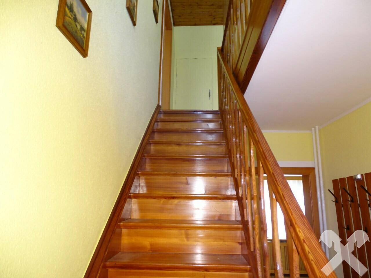 Holztreppe mit gelben Wänden, die in das obere Stockwerk führt.