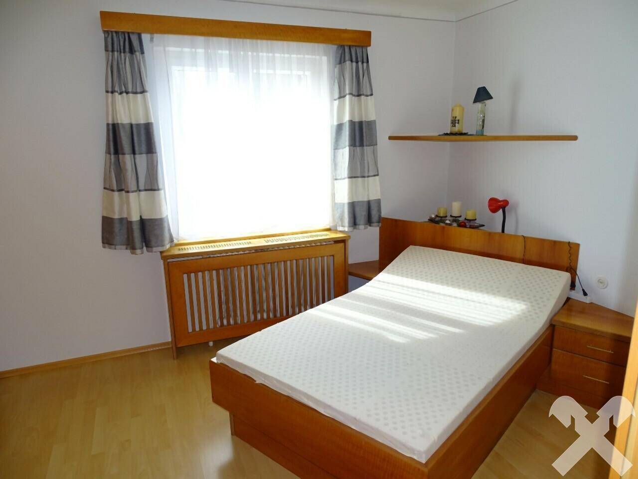 Schlafzimmer mit Doppelbett, Nachttischen und Fenster mit gestreiften Vorhängen.