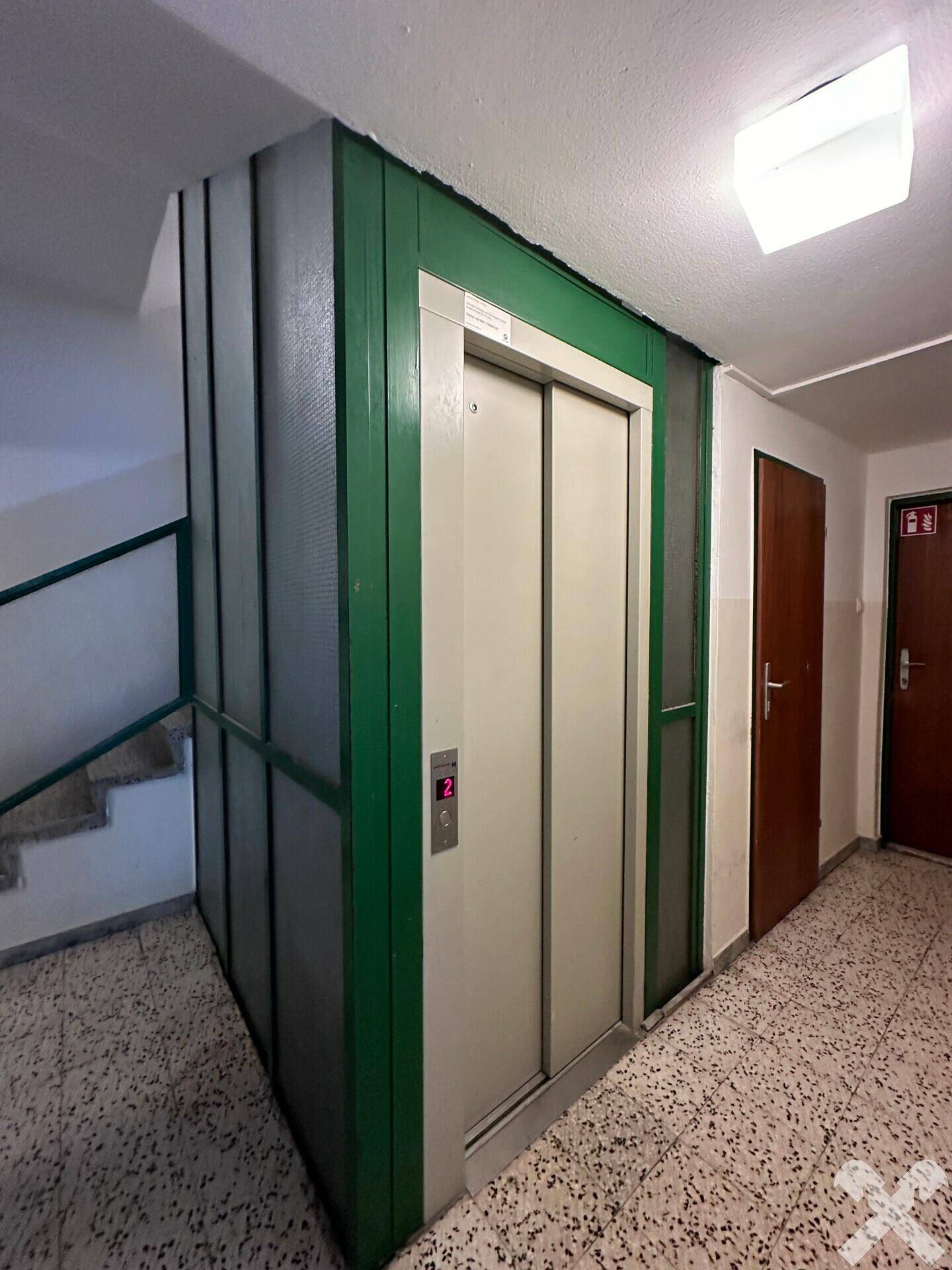 Aufzug in einem Mehrfamilienhaus, umgeben von Treppenhaus und Flur.