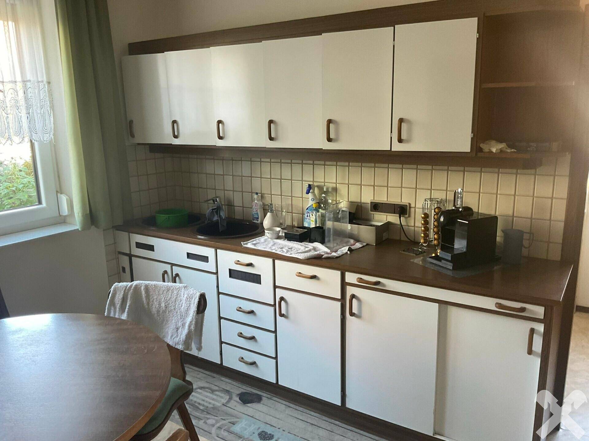 Küchenzeile mit weißen Schränken, Fliesenrückwand und Spülbecken.