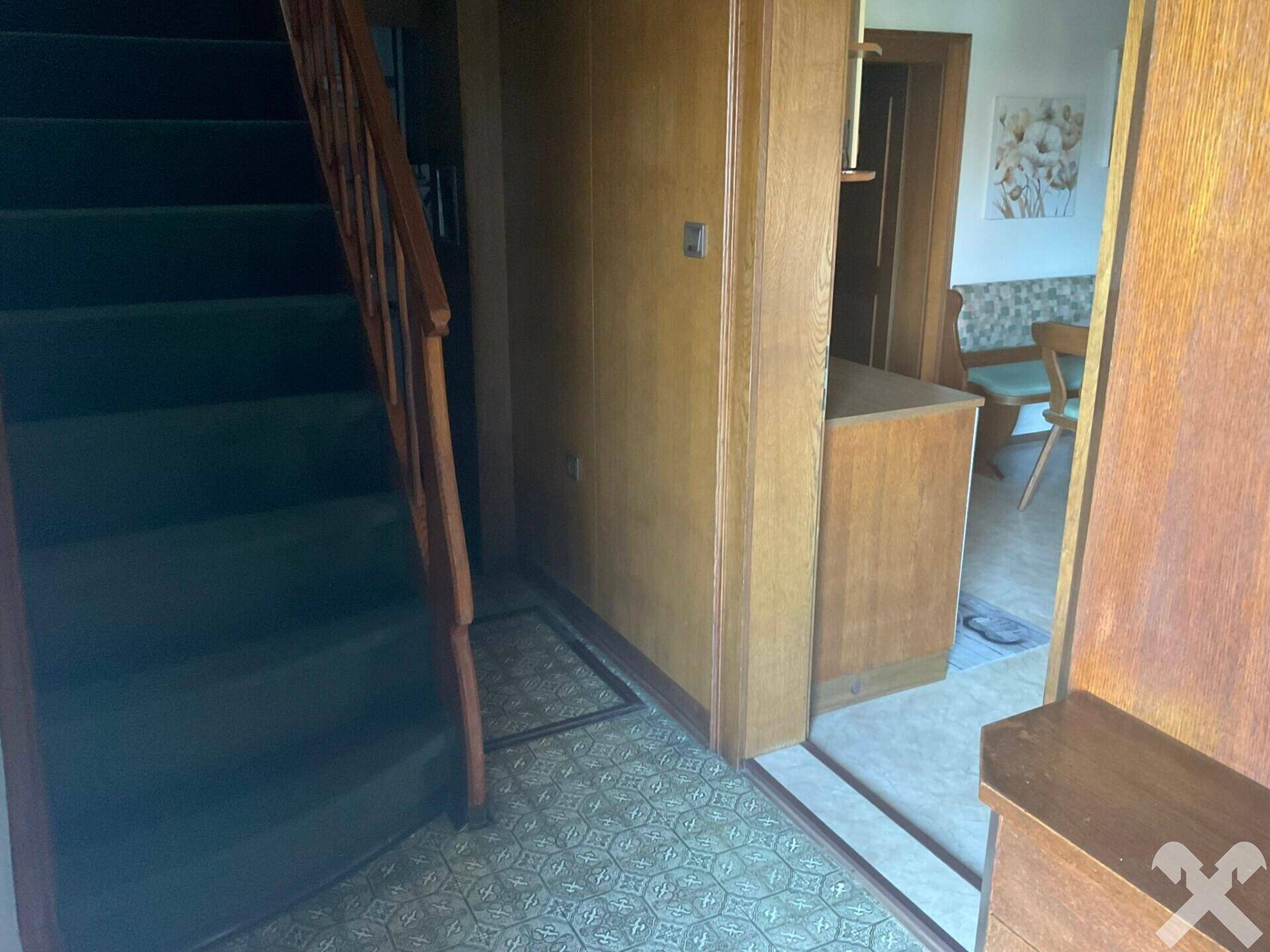 Eingangsbereich mit Teppichtreppe und Holzvertäfelung, führt in weitere Räume.