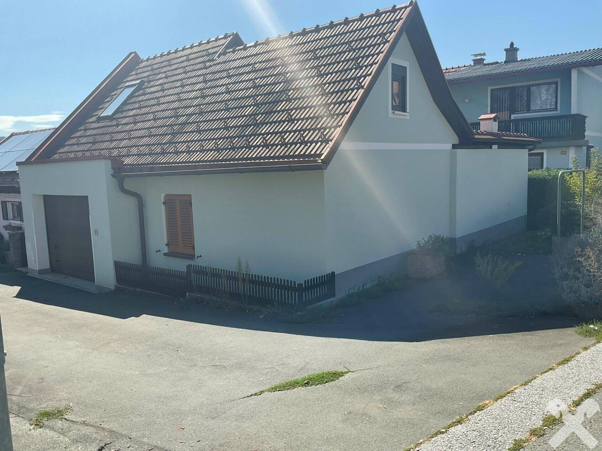 Seitenansicht des Hauses mit Garage, Satteldach und kleiner Gartenfläche.