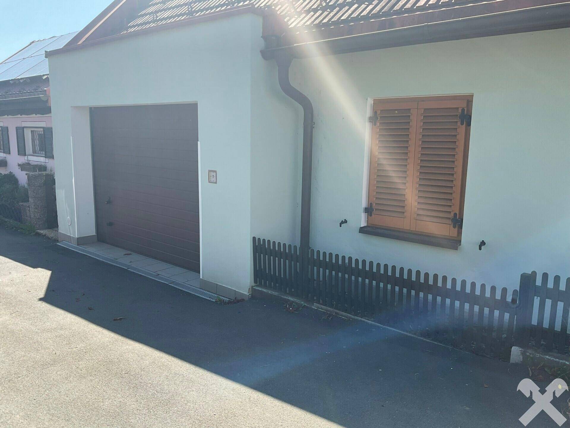 Nahaufnahme der Garage und eines Fensters mit Holzläden an der Hausseite.