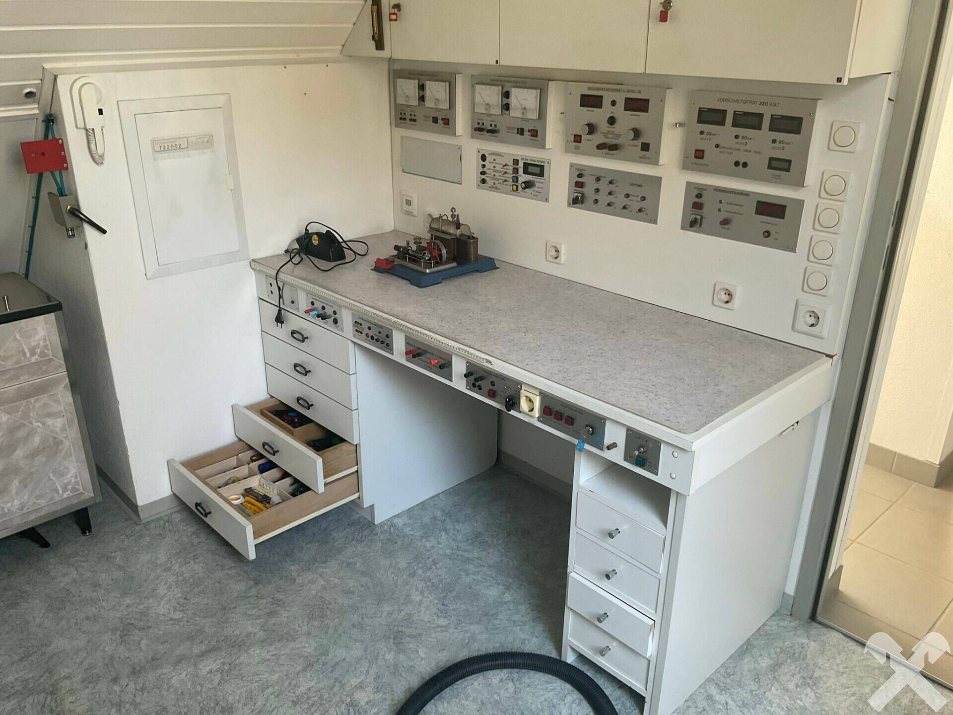 Werkstatt oder Hobbyraum mit umfangreicher Arbeitsplatte und vielen Geräten.