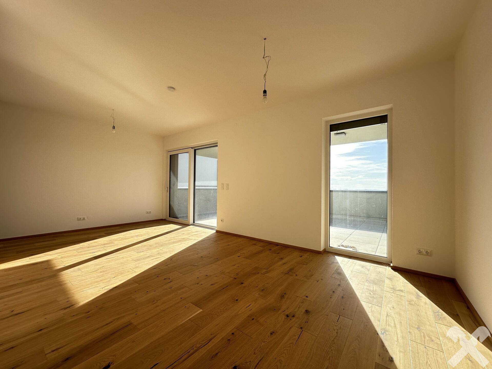 Geräumiges, helles Zimmer mit Eichenparkett und Zugang zu einer großen Terrasse, ideal für Wohn- oder Essbereich.