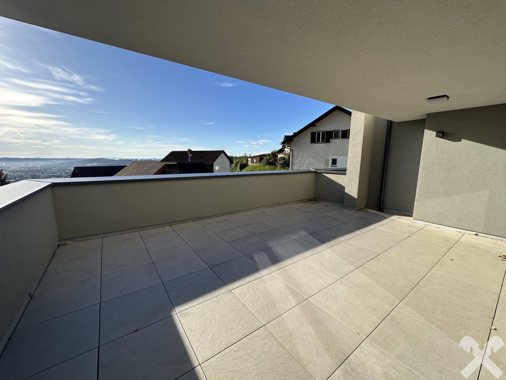 Großzügige, geflieste Terrasse mit weitem Ausblick über die Landschaft, perfekt für entspannte Stunden im Freien.