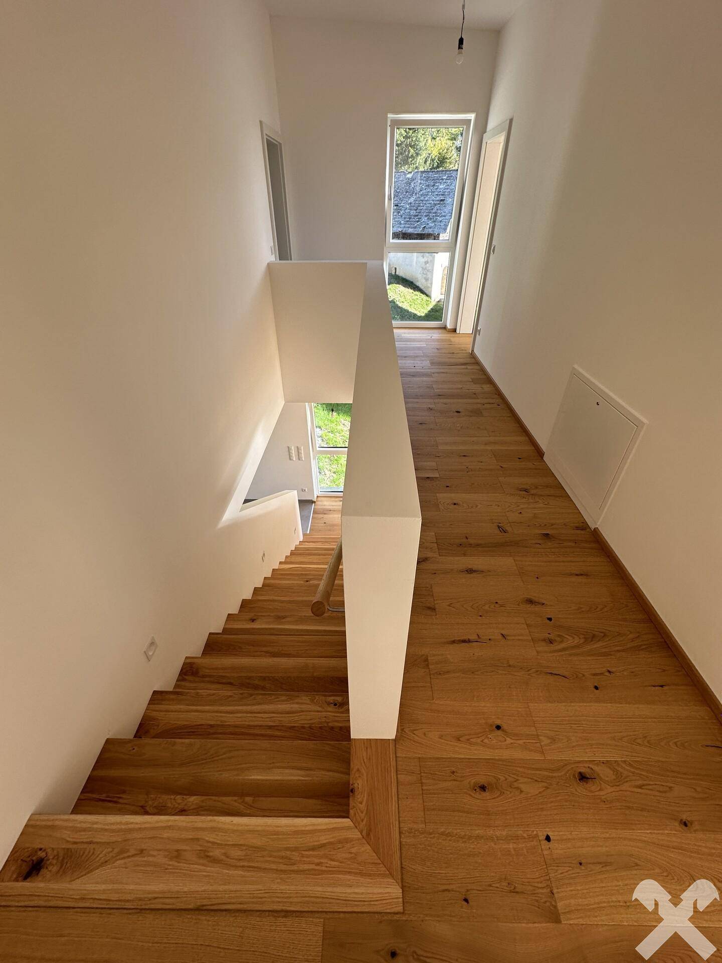 Heller Flur mit Eichenparkett und moderner Holztreppe, die zu den oberen Etagen führt.