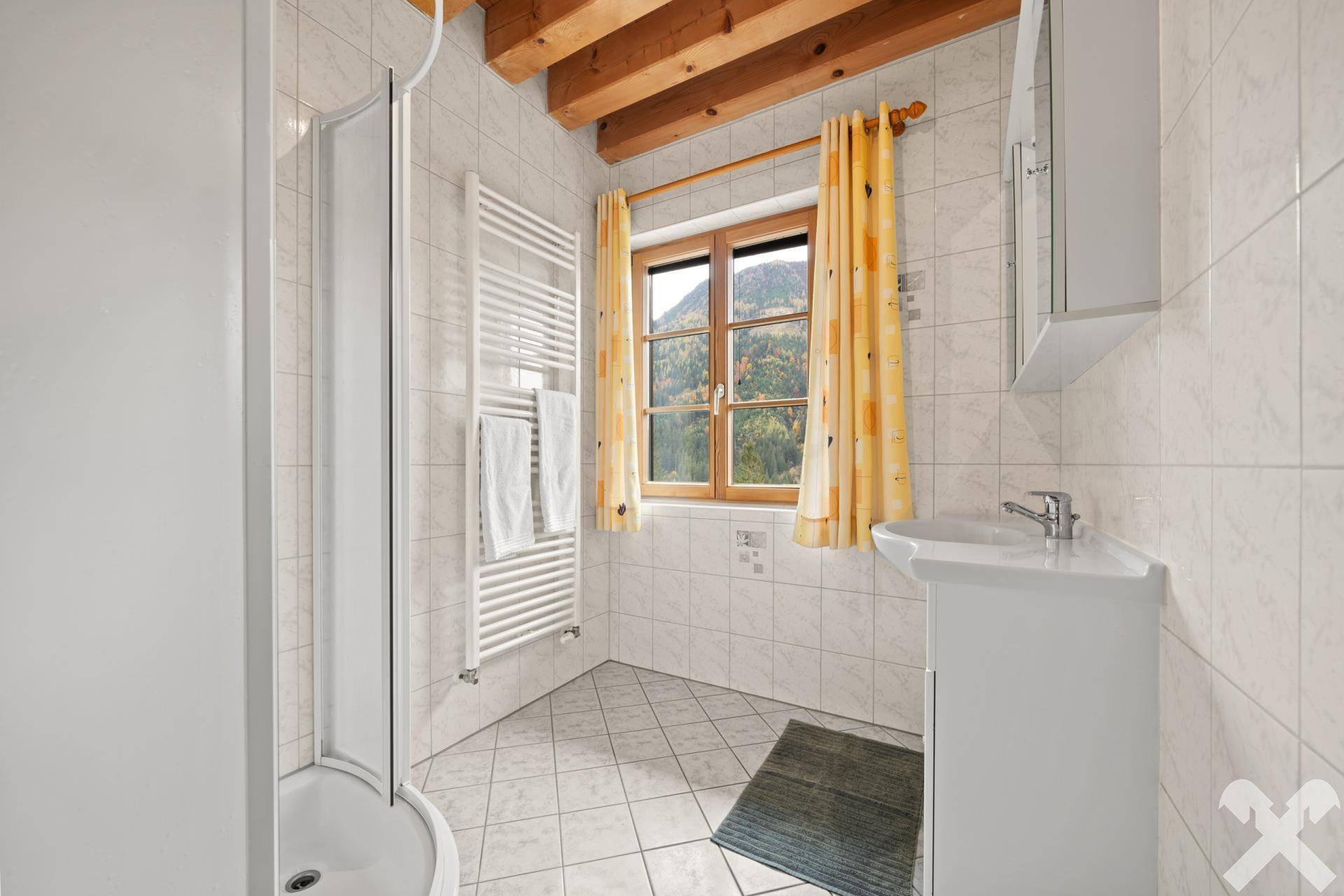 Helles Badezimmer mit Duschkabine, weißen Fliesen und einem Fenster mit Bergblick, funktional und sauber.