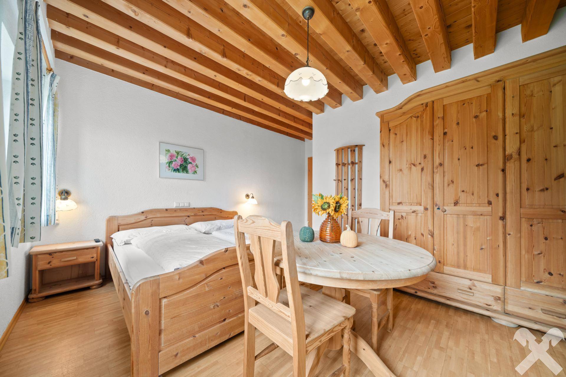 Gemütliches Schlafzimmer mit Holzbalkendecke, Holzboden und traditionellen Kiefernmöbeln, bietet eine warme Atmosphäre.