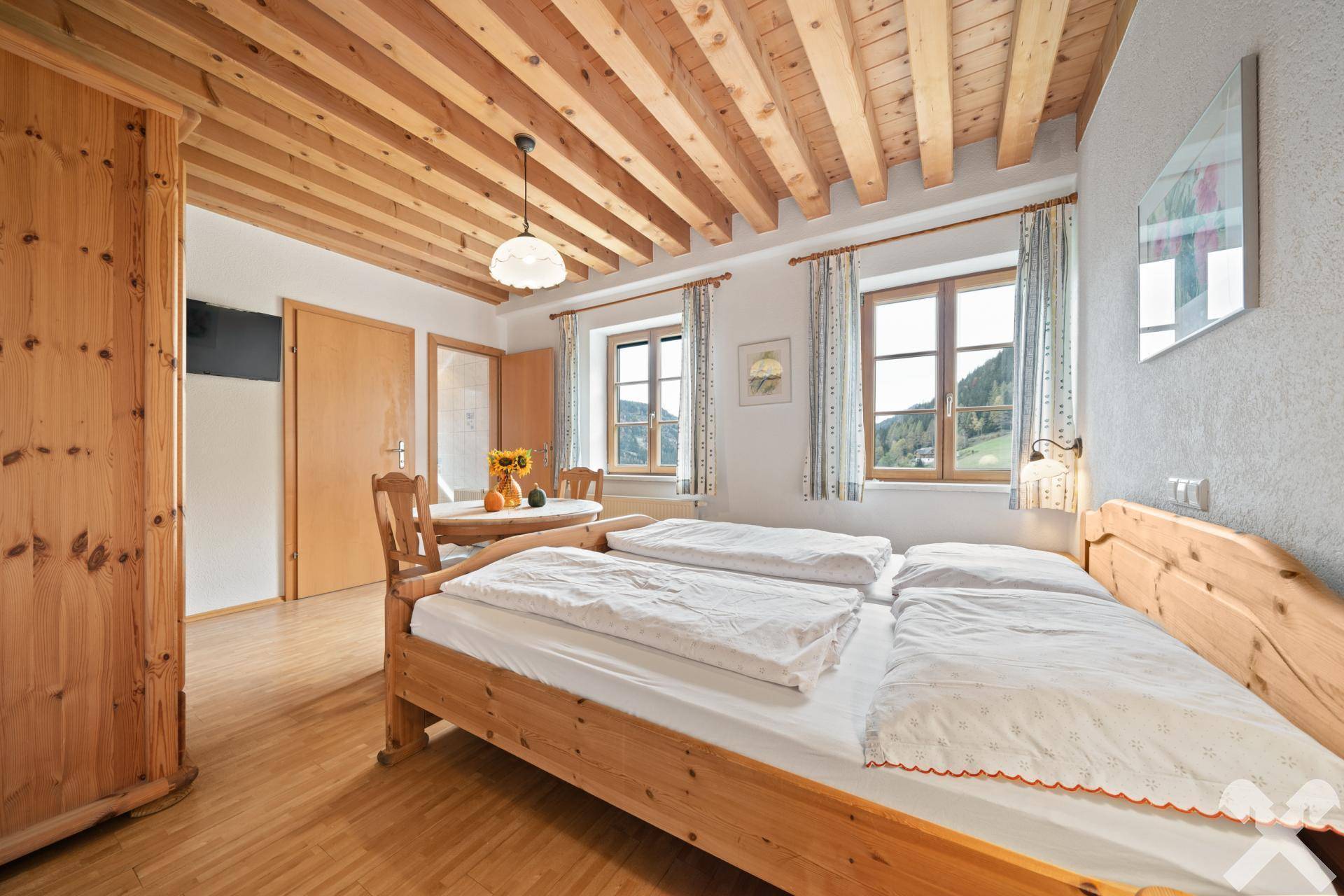 Helles Schlafzimmer mit Holzbalkendecke, Holzboden und traditionellen Holzbetten, bietet eine angenehme Wohnatmosphäre.