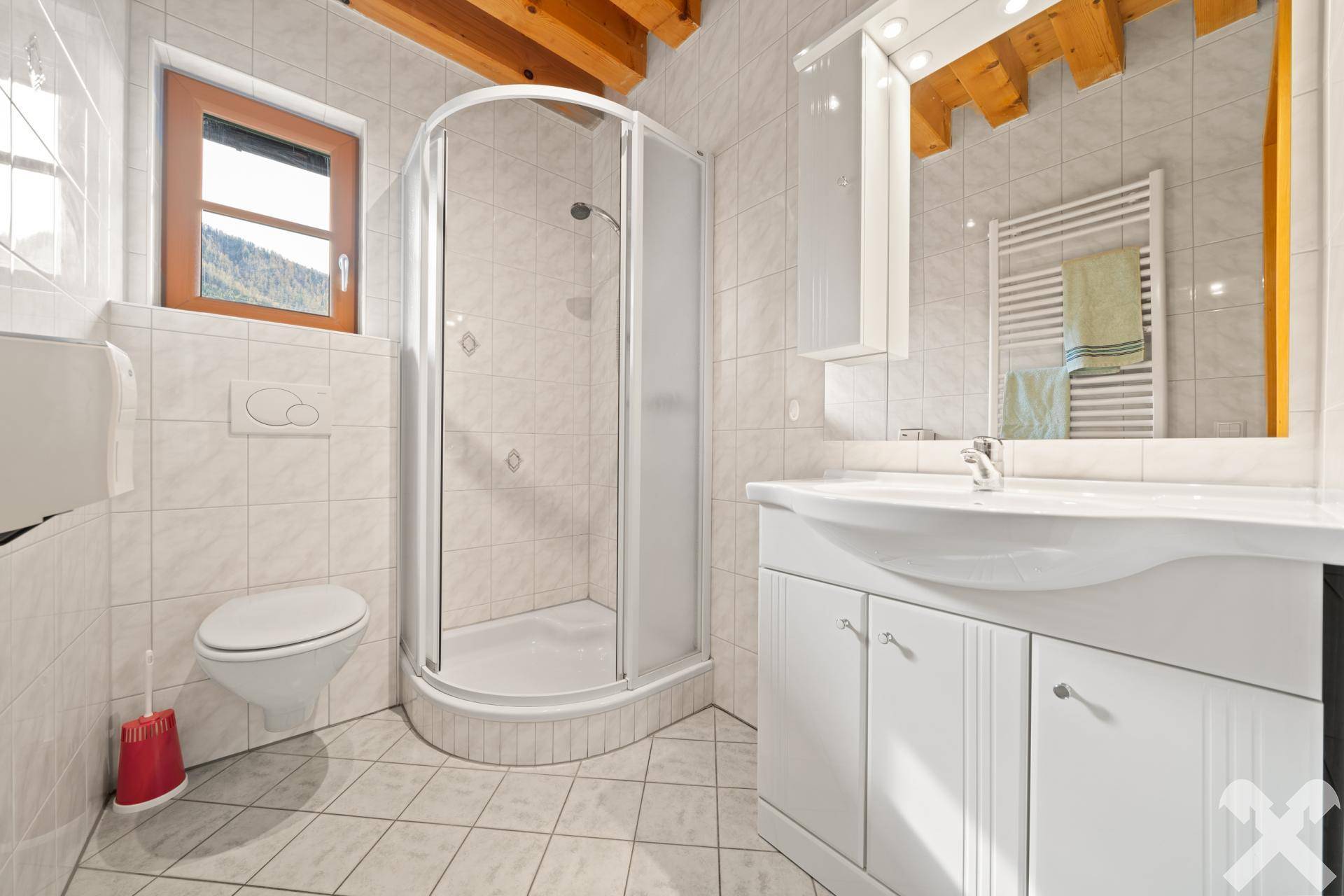 Kompaktes Badezimmer mit Duschkabine, Toilette, Waschtisch und weißen Fliesen, hell und praktisch eingerichtet.