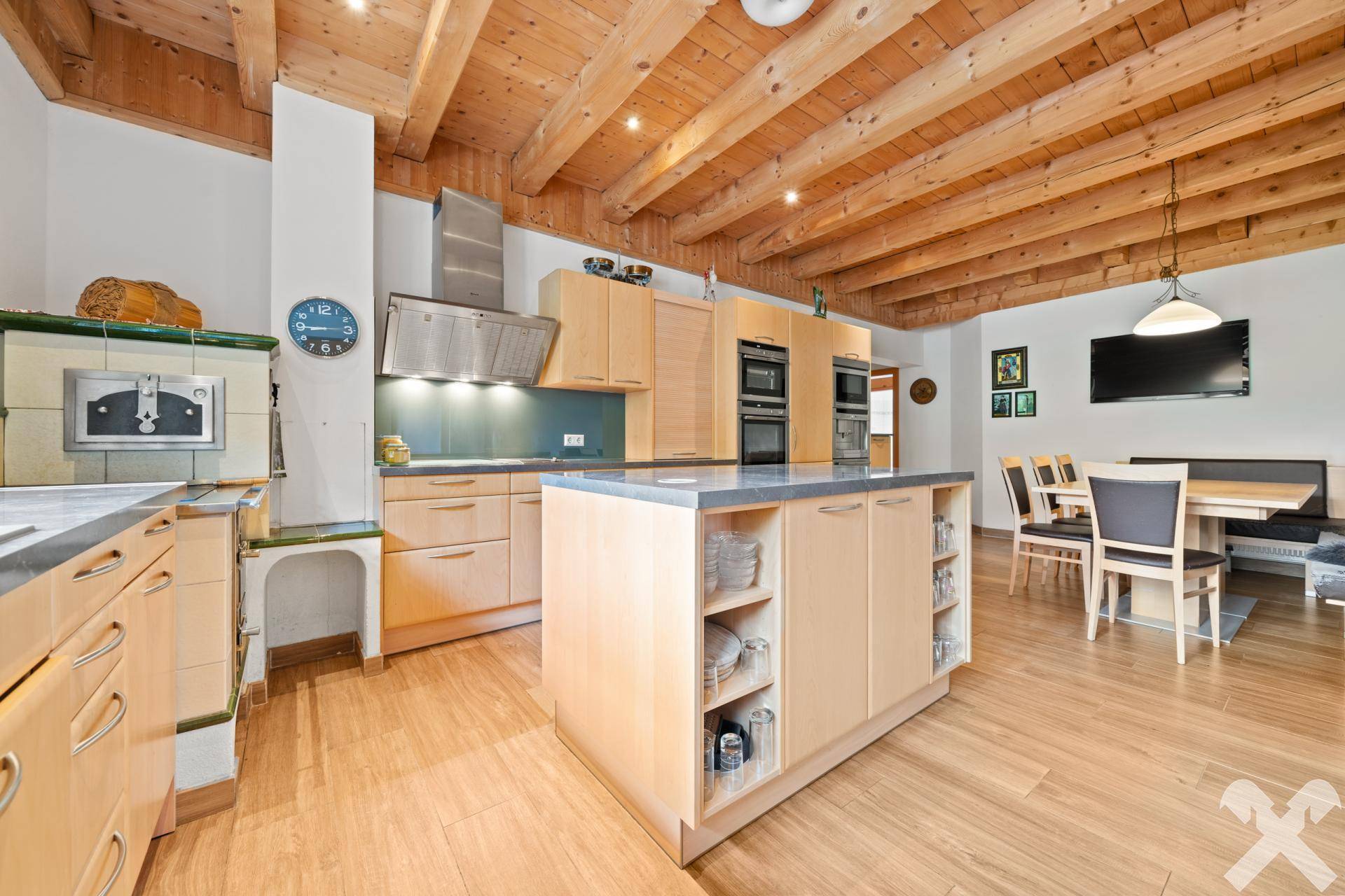 Moderne Küche mit Kochinsel, integrierten Geräten und angrenzendem Essbereich mit Holzbalkendecke, offen und hell.