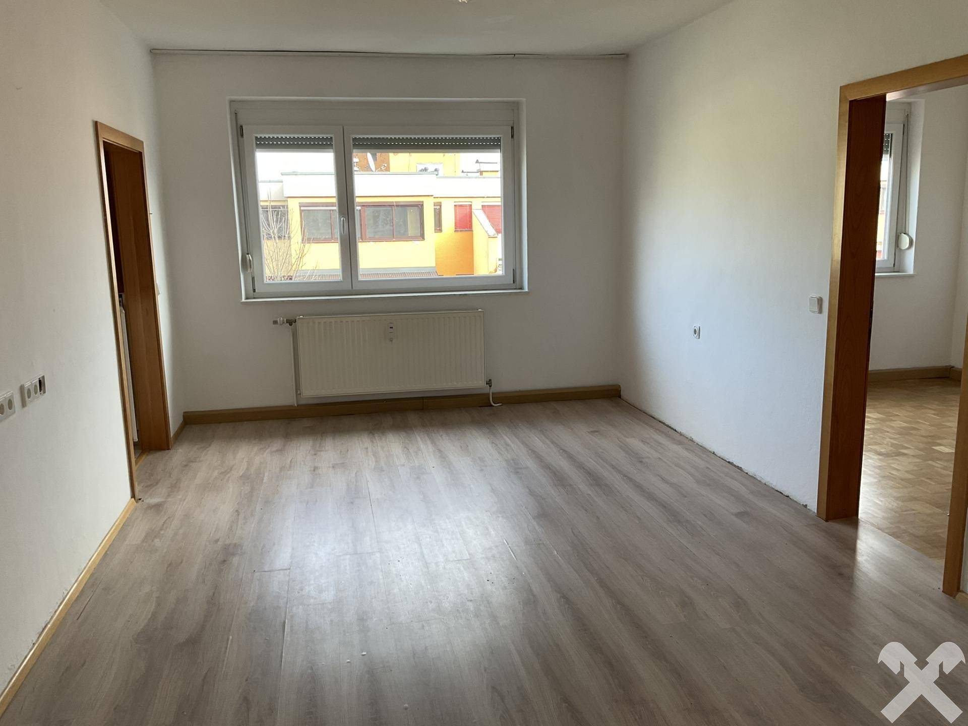 Geräumiges Zimmer mit Laminatboden und großem Fenster, bietet vielseitige Nutzungsmöglichkeiten.