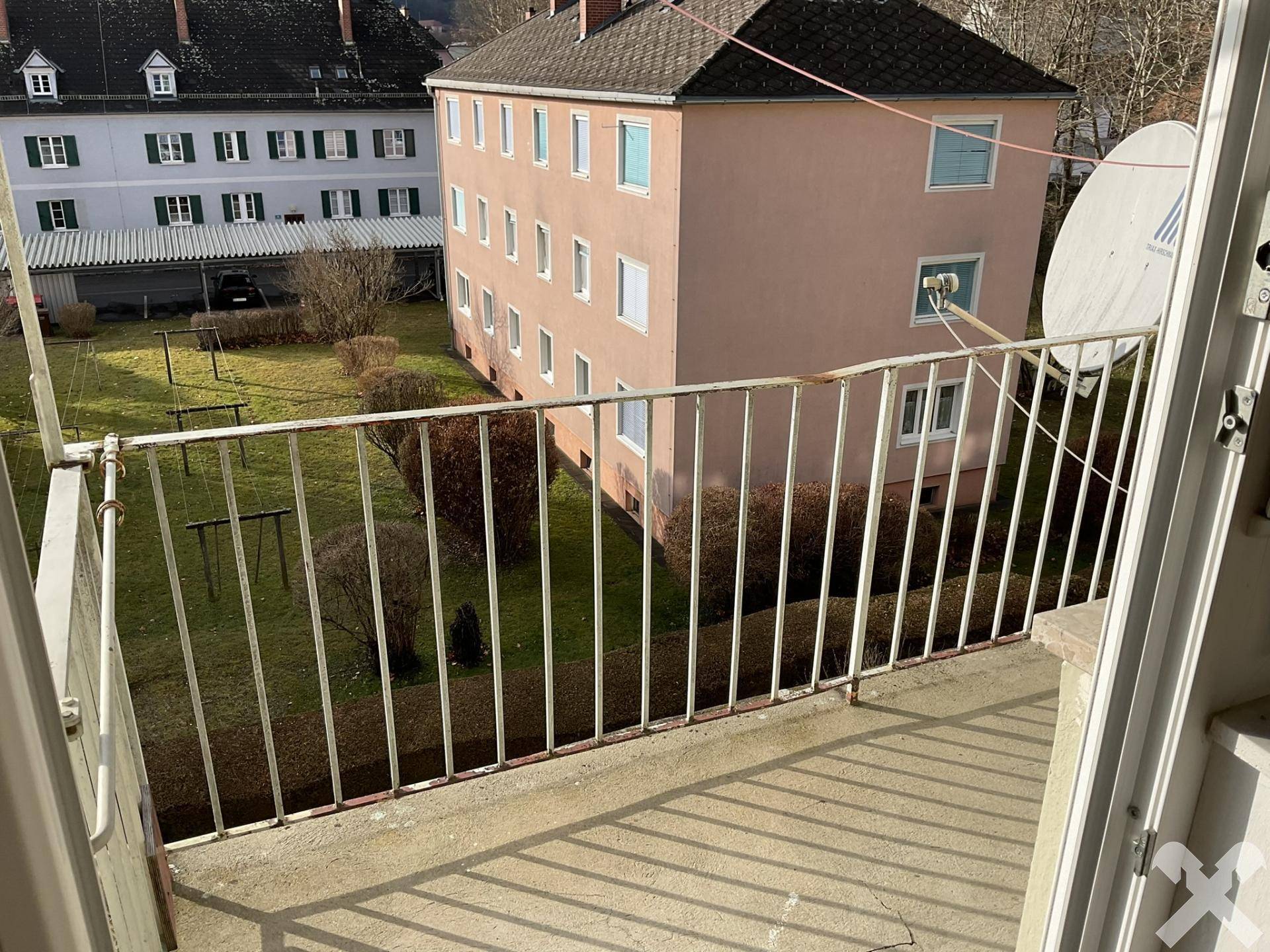 Kleiner Balkon mit Metallgeländer und Blick auf den Innenhof und umliegende Gebäude.