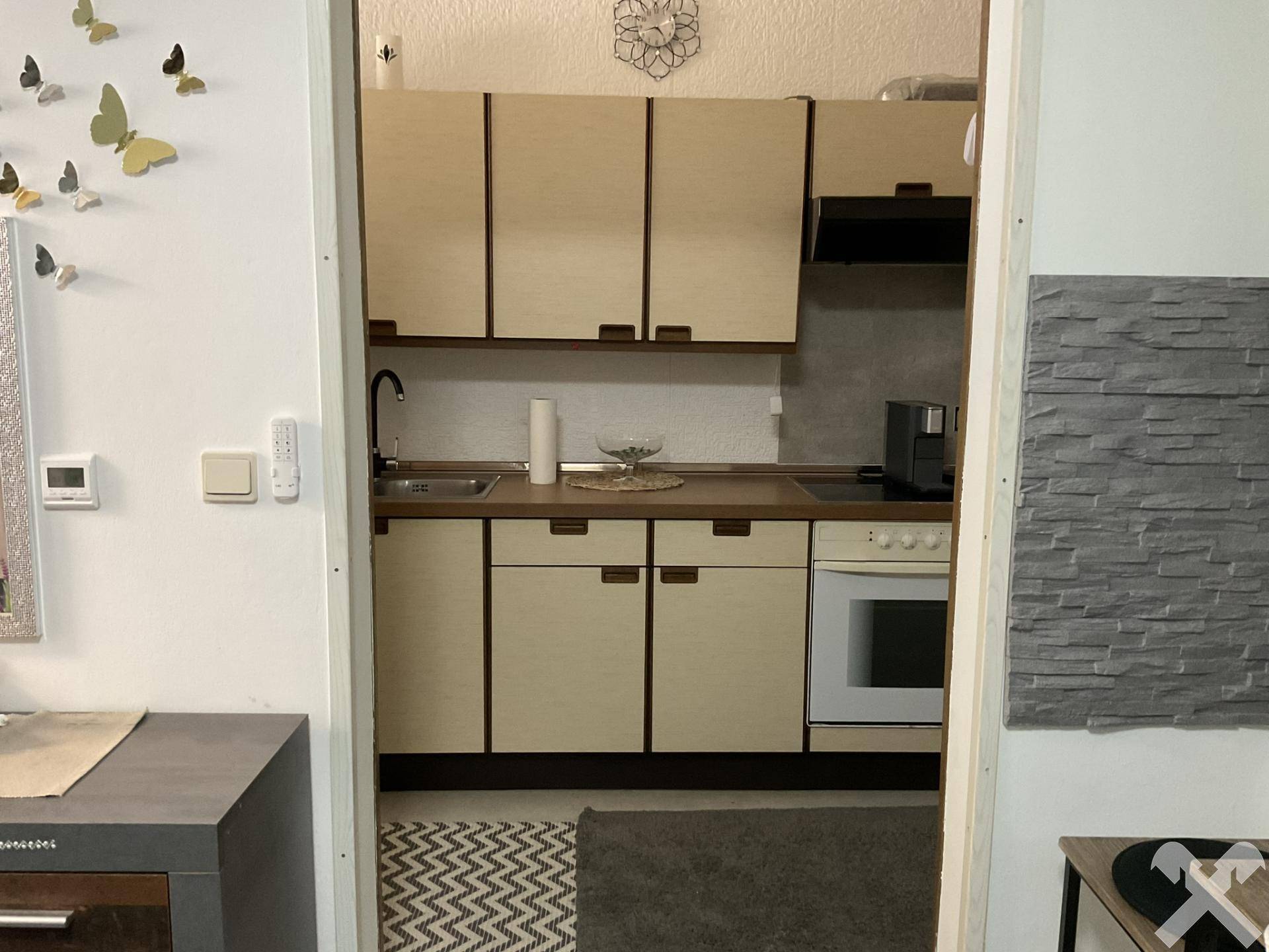 Kompakte Einbauküche mit hellen Schränken und integriertem Backofen.