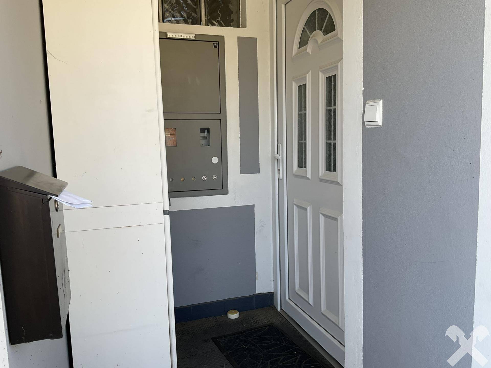 Eingangsbereich des Hauses mit Haustür und Zählerkasten an der Fassade.
