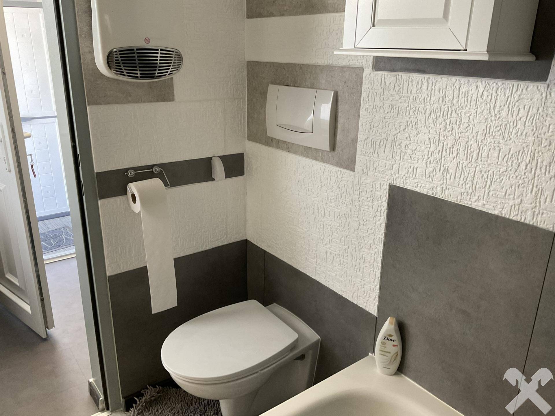 Badezimmer mit wandhängendem WC und strukturierten Wandfliesen in modernem Design.