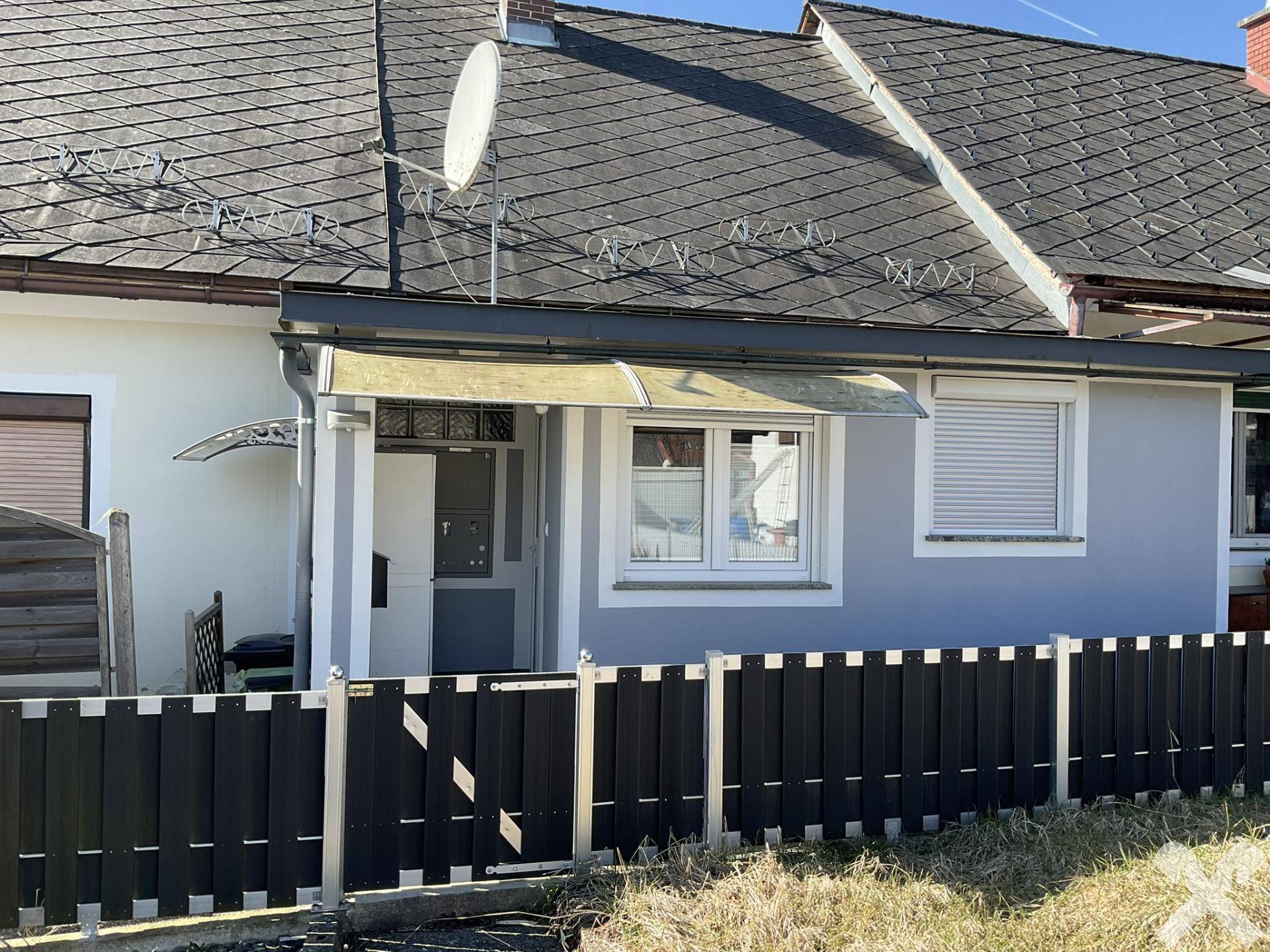 Außenansicht des Hauses mit Satteldach, Rollläden und Gartenzaun im Vordergrund.