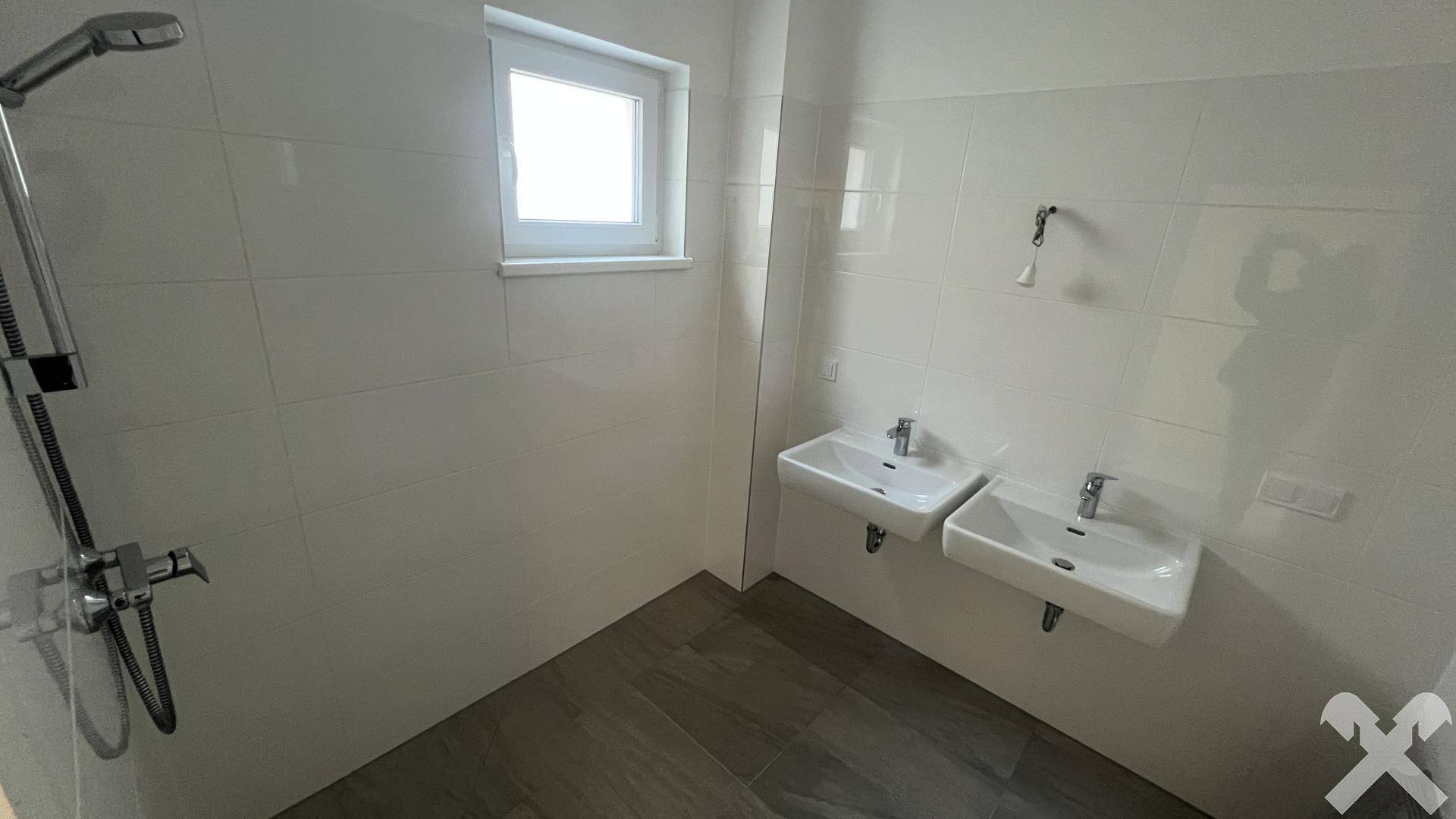 Modernes Badezimmer mit zwei Waschbecken, Dusche und hellen Fliesen.