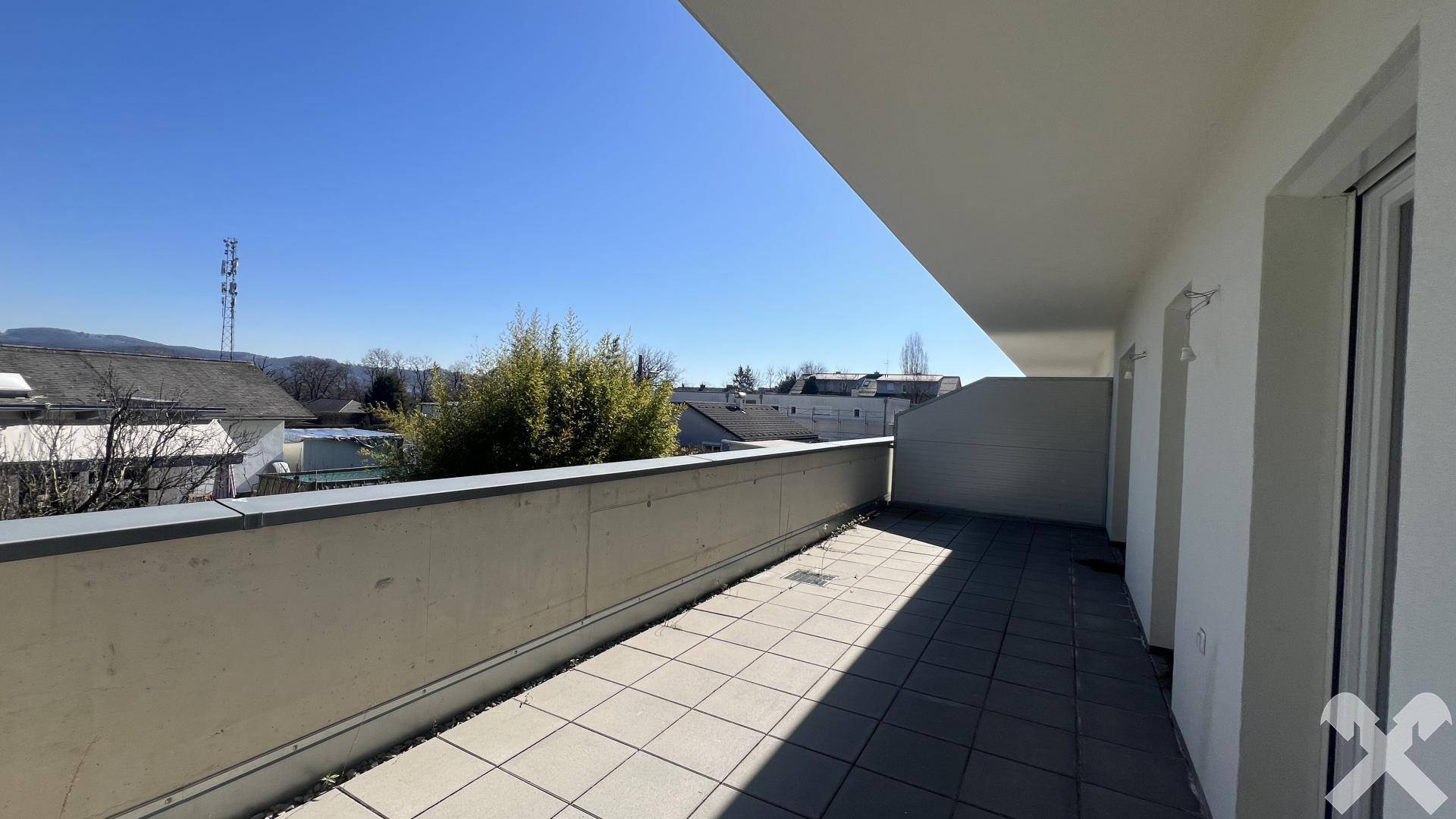 Große geflieste Terrasse mit Blick auf die Umgebung und blauen Himmel.